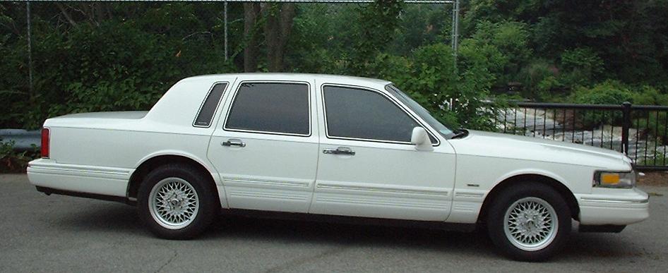 White Lincoln Town Car, side view. Watermark reads SUPERMOTORS.NET