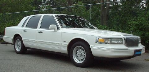 1997 Ford Crown Victoria - This white sedan has a distinctive grille and body style, suggesting a mid-1990s model year.