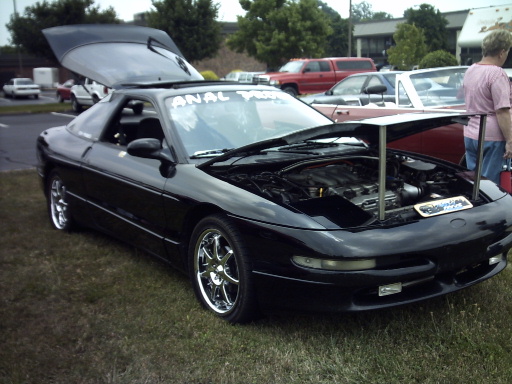 Black 1995 Ford Probe with hood and trunk open, showing engine and interior. Chrome wheels visible