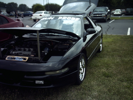 Black 1995 Ford Probe with hood and trunk open, parked on grass