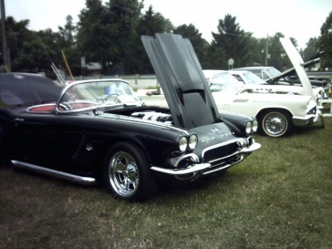 1995 Ford Probe - A black convertible is parked on grass with its hood open, alongside other vehicles.