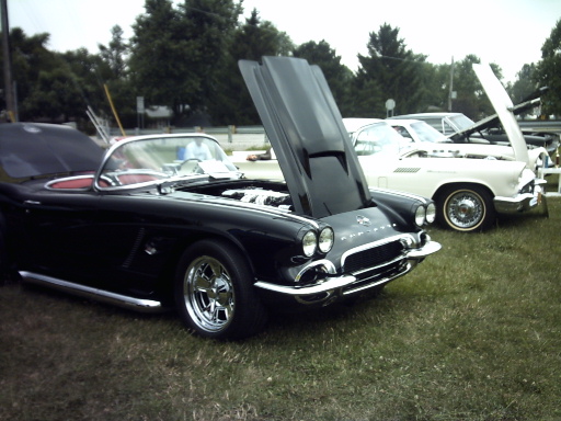 Black convertible with hood open, chrome trim, and aftermarket wheels