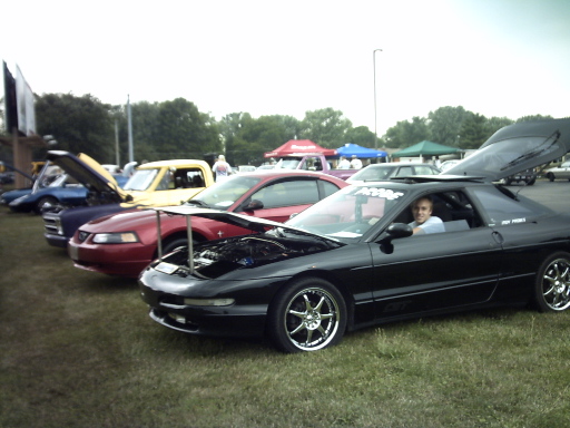 Black Ford Probe with aftermarket wheels and open trunk, driver visible