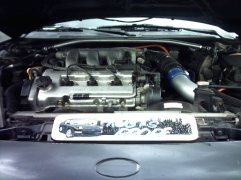 1995 Ford Probe - The engine bay of a car is shown, with a decorative plate a car illustration.