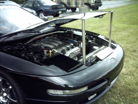 1995 Ford Probe - The engine bay of a black 1995 Ford Probe is visible with the hood propped open, parked outdoors.