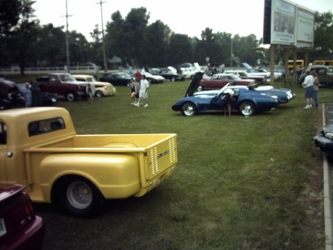 1995 Ford Probe - An outdoor car show features a variety of vehicles, including a yellow pickup truck and a blue sports car.