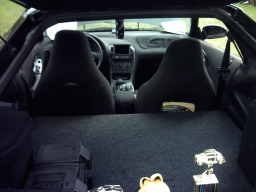Interior view of a 1995 Ford Probe showing front seats, dashboard, and cargo area with trophies