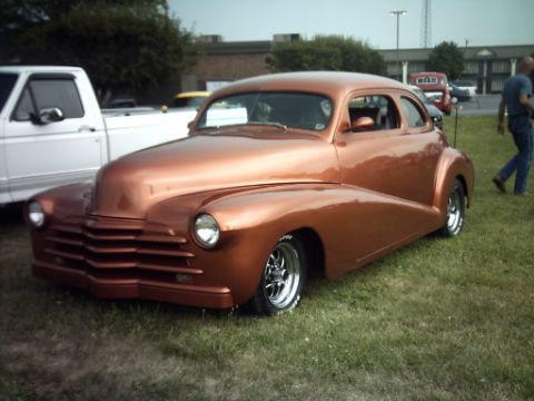 1995 Ford Probe - A copper customized coupe is parked on grass next to a white pickup truck at an outdoor event.