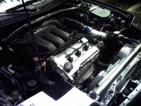 1995 Ford Probe - The engine compartment of a car is shown, with various hoses, wires, and mechanical parts.