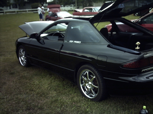 Black 1995 Ford Probe with hood and trunk open, parked on grass