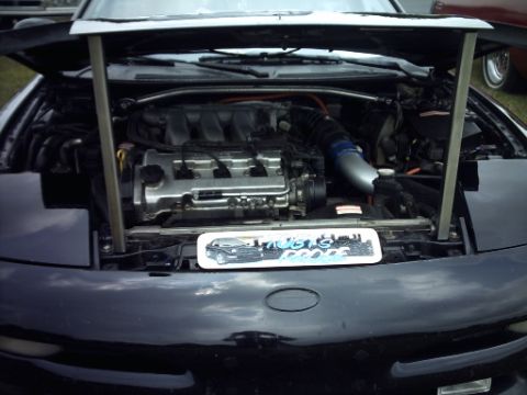1995 Ford Probe - The engine compartment of a black car is displayed with the hood fully open, revealing the engine and its components.