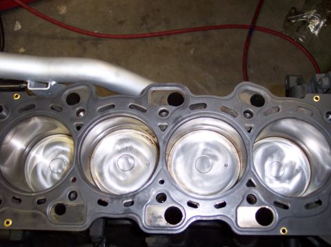 1999 Mitsubishi Mirage - Close-up view of an engine block's cylinder head gasket and pistons, indicating internal engine components.