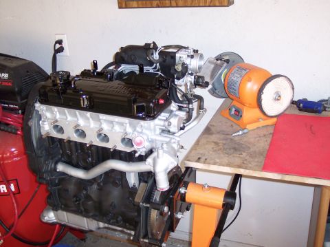 1999 Mitsubishi Mirage - Engine on a stand with a bench grinder nearby.