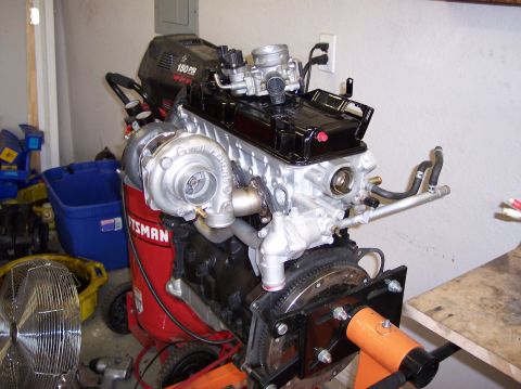 1999 Mitsubishi Mirage - Engine assembly with a Garrett turbocharger mounted, resting on an engine stand.