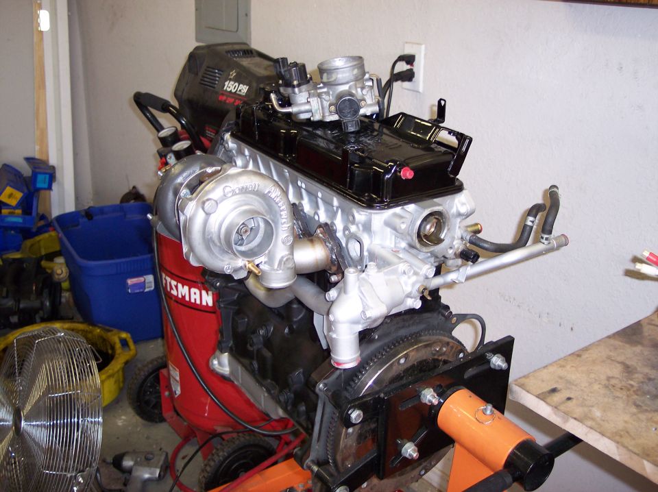 Rebuilt inline-4 engine with Garrett turbo on a stand in a garage
