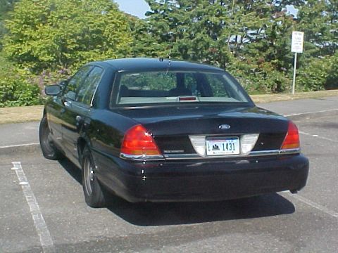 1999 Ford Crown Victoria - Black Ford Crown Victoria sedan parked in a lot with trees in the background.