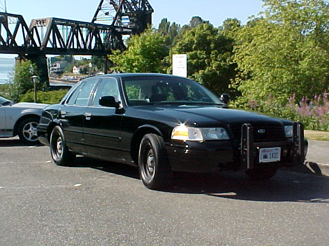 Black Ford Crown Victoria police car, front 3/4 view, with push bumper and license plate 1431