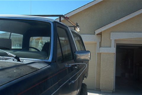 1986 Ford Bronco - Dark blue Ford Bronco with a roof rack is parked in front of a house with a garage.