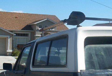 1986 Ford Bronco - A 1986 Ford Bronco is parked in front of a house, with a shovel attached to its roof rack.