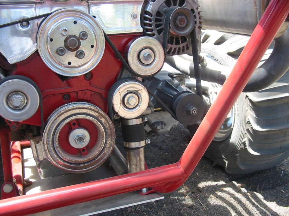 Close-up of a red engine block with pulleys and belts, including an alternator