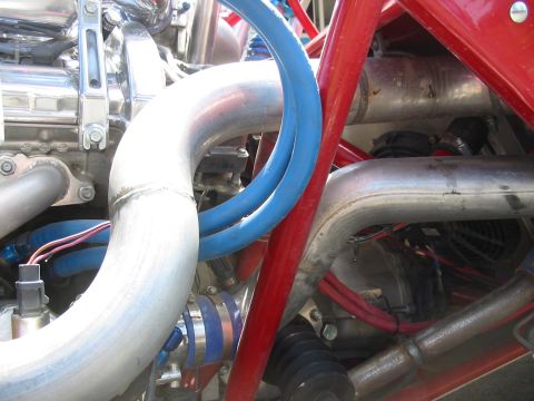 1993 Ford Taurus - Tight close-up of a custom engine bay's plumbing, showing large mandrel-bent aluminum intake tubing, a blue silicone coupler and blue-anodi…