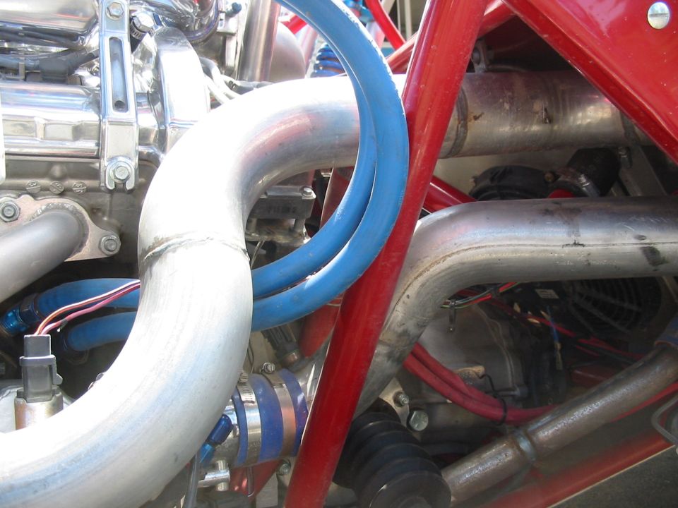 Close-up of aluminum intake tubing, blue silicone coupler and AN lines in a red tube-frame engine bay