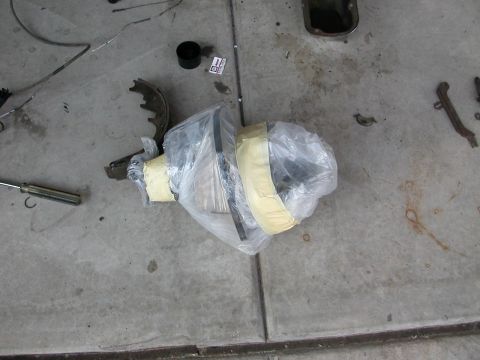 1984 Ford Bronco - Various automotive parts, including a differential and brake components, are laid out on a concrete surface.