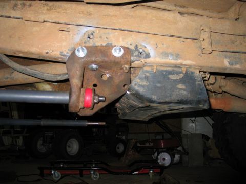 1995 Ford Bronco - Close-up of a vehicle's undercarriage, focusing on a suspension component with visible red bushings and a gray bar.