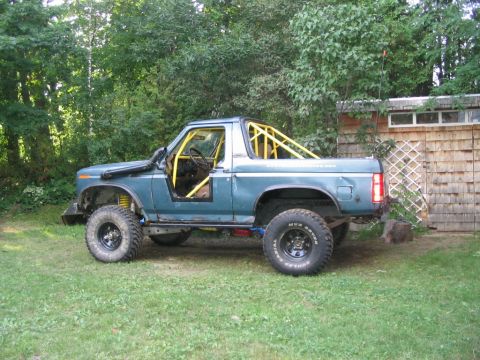 1986 Ford Bronco - This modified Ford Bronco features a yellow roll cage and snorkel, suggesting off-road use.