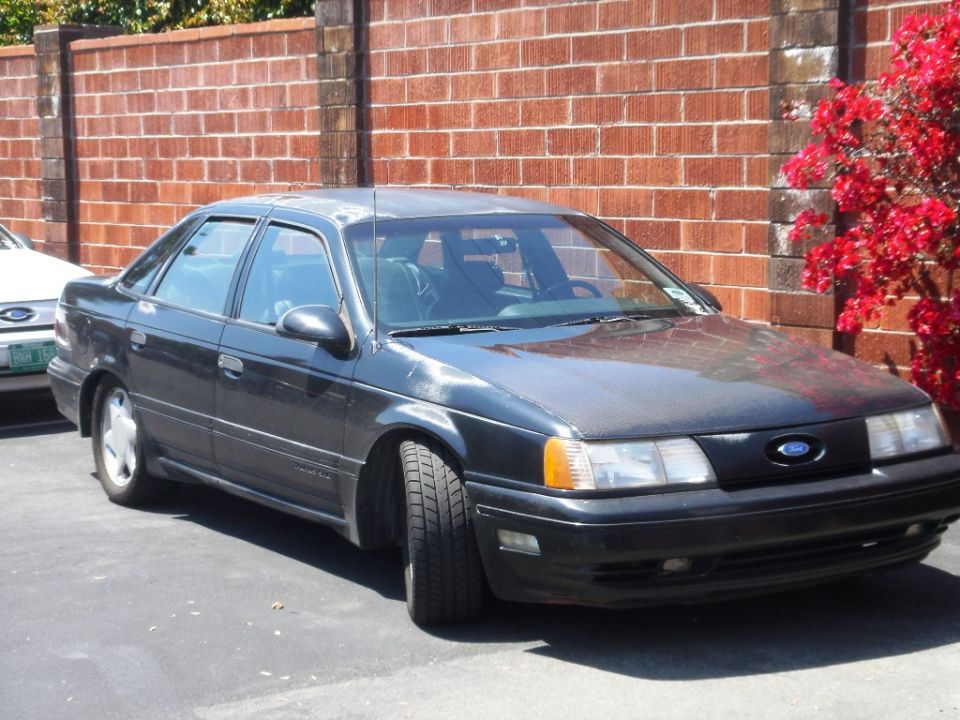 Dark 1991 Ford Taurus 3q-front view parked by brick wall