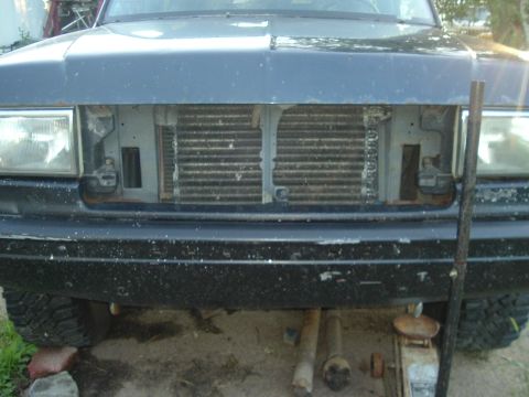 1989 Ford Bronco - Front view of a dark blue Ford Bronco with its grille removed, revealing the radiator. The vehicle appears to be undergoing maintenance.
