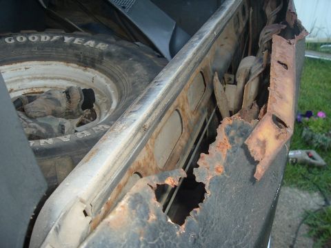 1989 Ford Bronco - Spare tire and severely rusted metal frame of a vehicle.