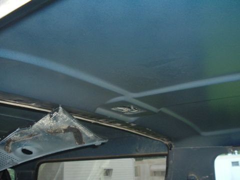 1989 Ford Bronco - Interior view of a vehicle's blue ceiling, showing damage to a detached trim panel.