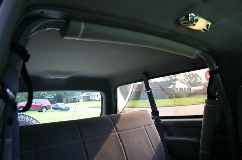 1994 Ford Bronco - View from the rear seat shows the interior roll bar and a glimpse of two vehicles parked outside.