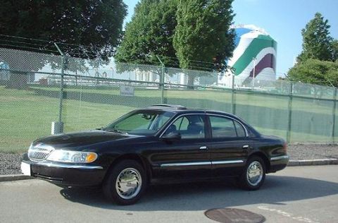 1997 Ford Crown Victoria - This black Lincoln Continental sedan is parked near a large industrial tank.