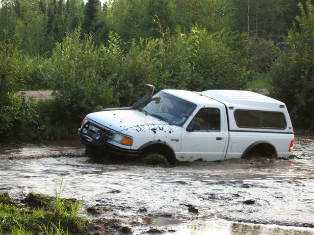 White pickup truck with a snorkel stuck in mud, front right tire submerged