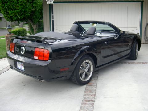 2005 Ford Mustang - Black 2005 Ford Mustang convertible parked in front of a garage.