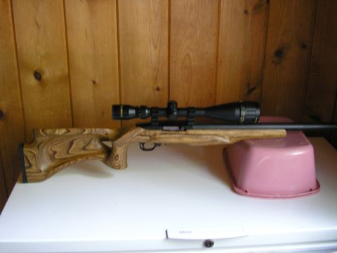 1990 Ford Probe - A rifle with a wooden stock and a scope is displayed on a white surface against a wood-paneled wall.