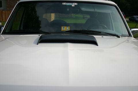 1994 Ford Bronco - Front view of a white SUV's hood, a prominent black air scoop.
