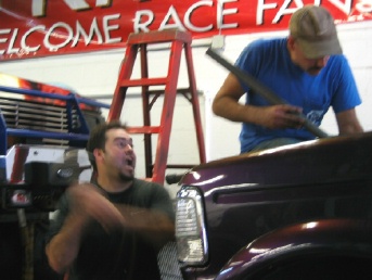 1994 Ford Bronco - Men are working on the interior of a vehicle, with a ladder and tools in the background.