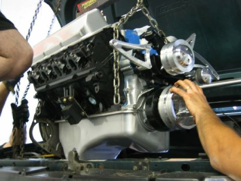 1994 Ford Bronco - An engine is being installed into a vehicle, with chains supporting its weight.