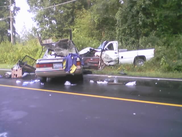 wrecked car and white truck on side of road
