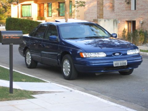 1995 Ford Taurus - A blue 1995 Ford Taurus is parked on the street next to a mailbox.