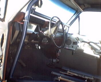 1981 Ford Bronco - The interior of a vehicle is shown, a steering wheel, dashboard, and a prominent roll cage.