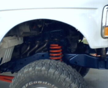 1981 Ford Bronco - Close-up view of the suspension system and tire on a white vehicle.