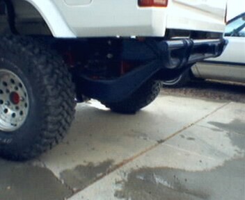 1981 Ford Bronco - Close-up view of the rear bumper and tire of a white SUV, with another vehicle partially visible in the background.