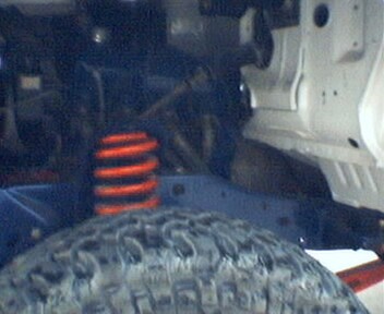 1981 Ford Bronco - This image shows a close-up view of a vehicle's suspension system, including a coil spring and a tire.
