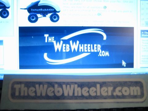 1990 Ford Bronco - TheWebWheeler.com decal sits in front of a monitor showing the blue site logo banner and forum post.