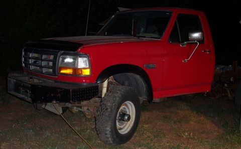 1990 Ford Bronco - This red pickup truck is shown from a 3/4 front angle, with an F-150 badge visible on the fender.