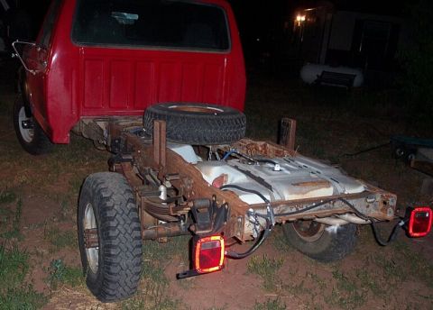 1990 Ford Bronco - Rear view of a red truck chassis, showing the fuel tank, spare tire, and suspension components.